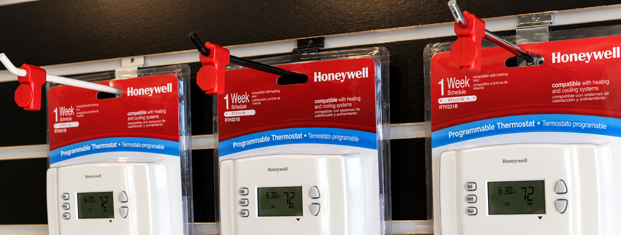 Red StopLocks on slatwall display hooks holding packaged thermostats